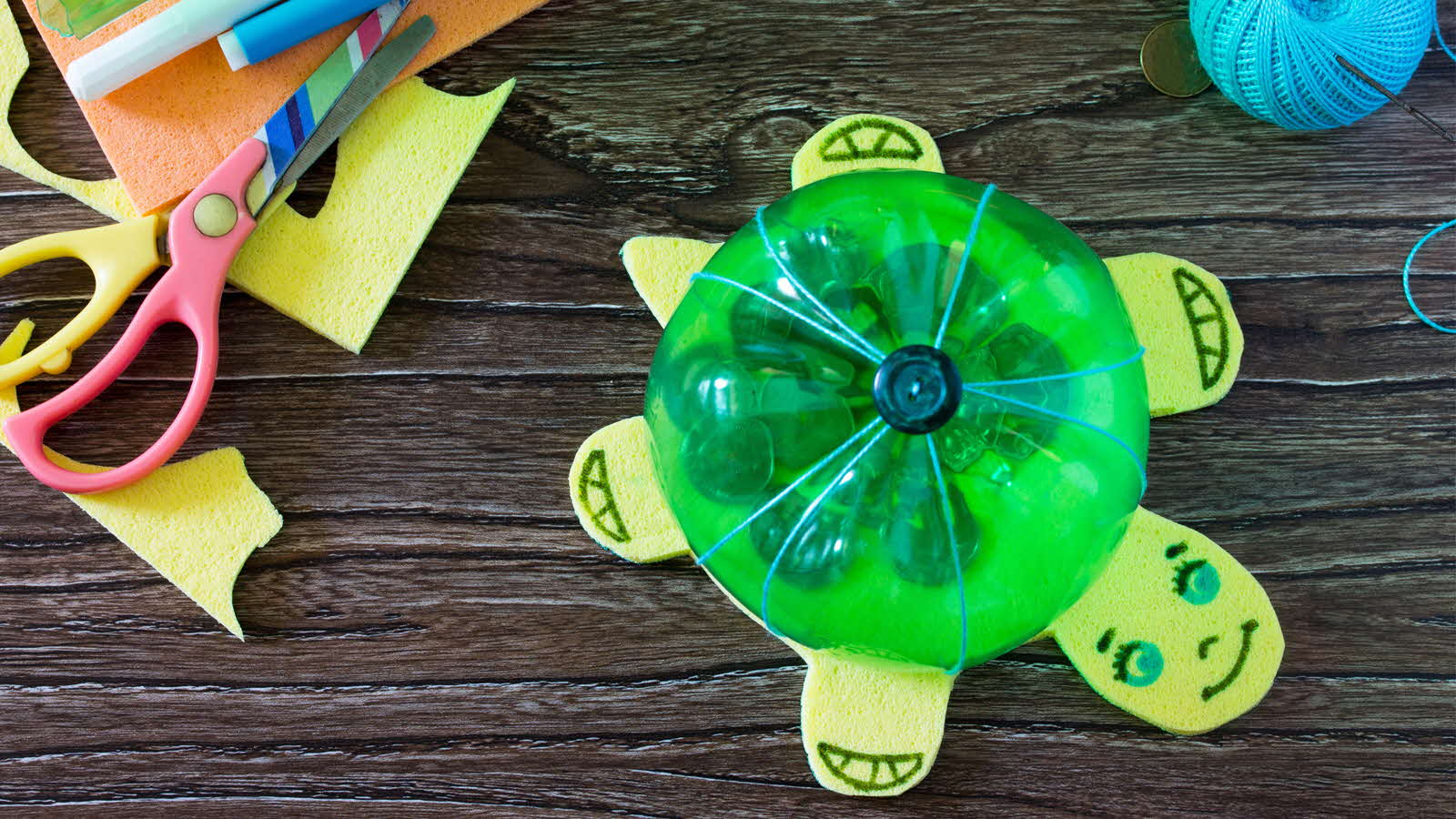 A creative turtle craft made from a plastic bottle and sponge cloth, repurposed into a coin bank.