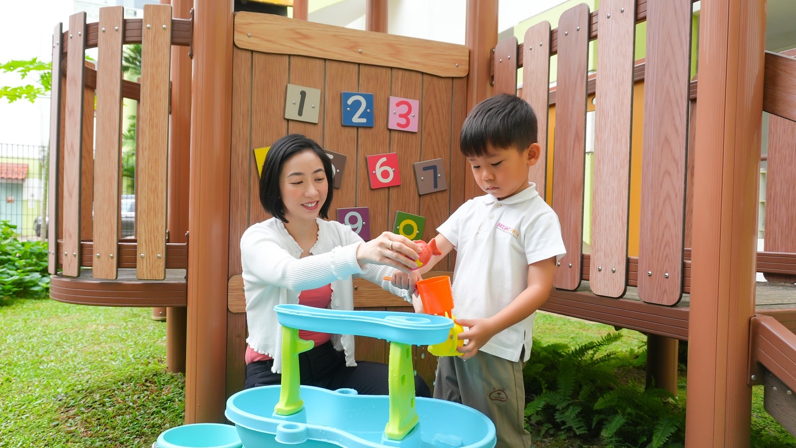 An educator with a child at water play