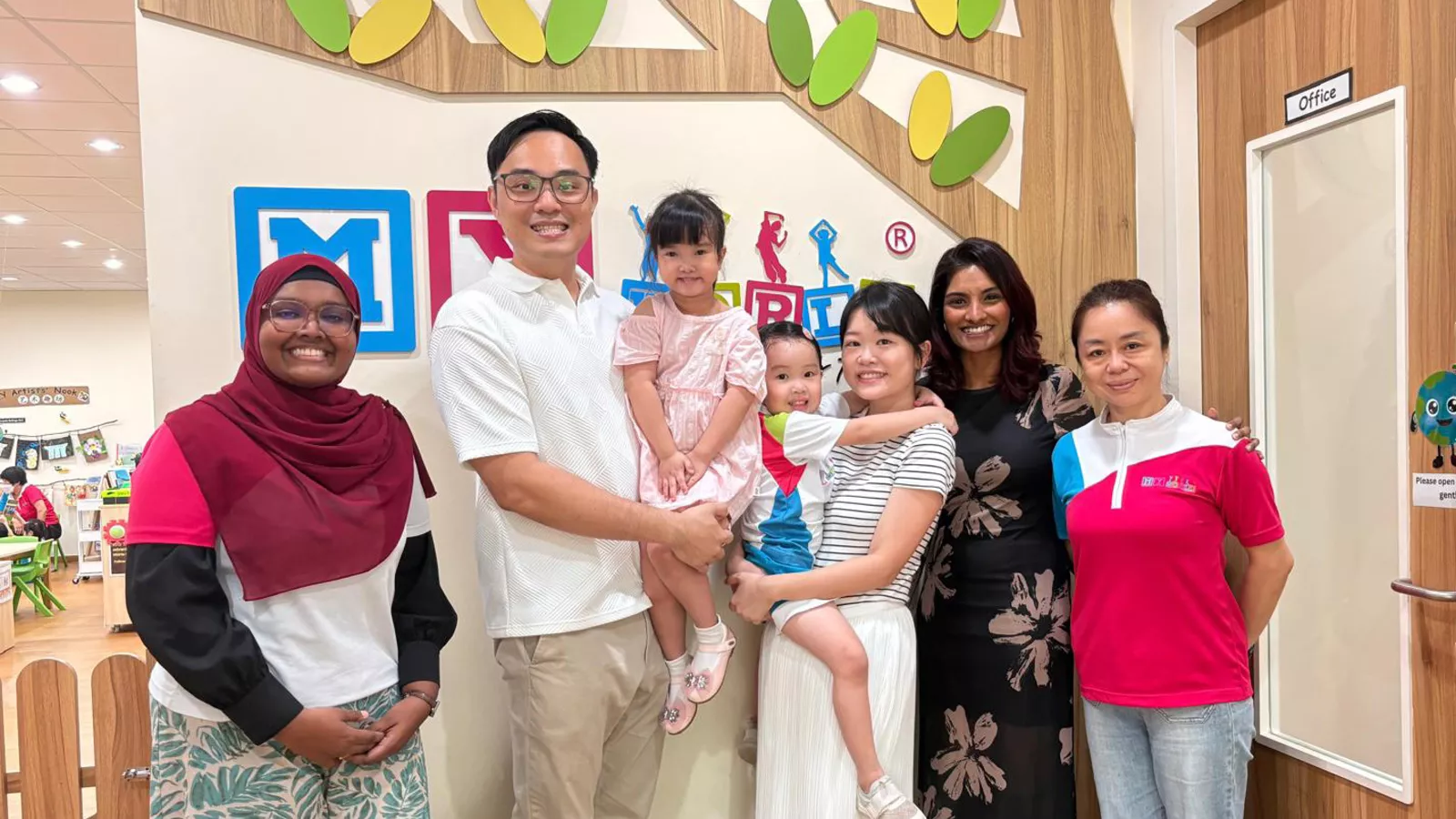 Kow Bi Xia and her family pose with her children’s educators, showcasing their strong parent-preschool partnership.