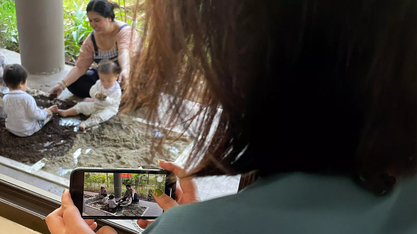 An educator records a video of infants engaging in sand play to document their learning.