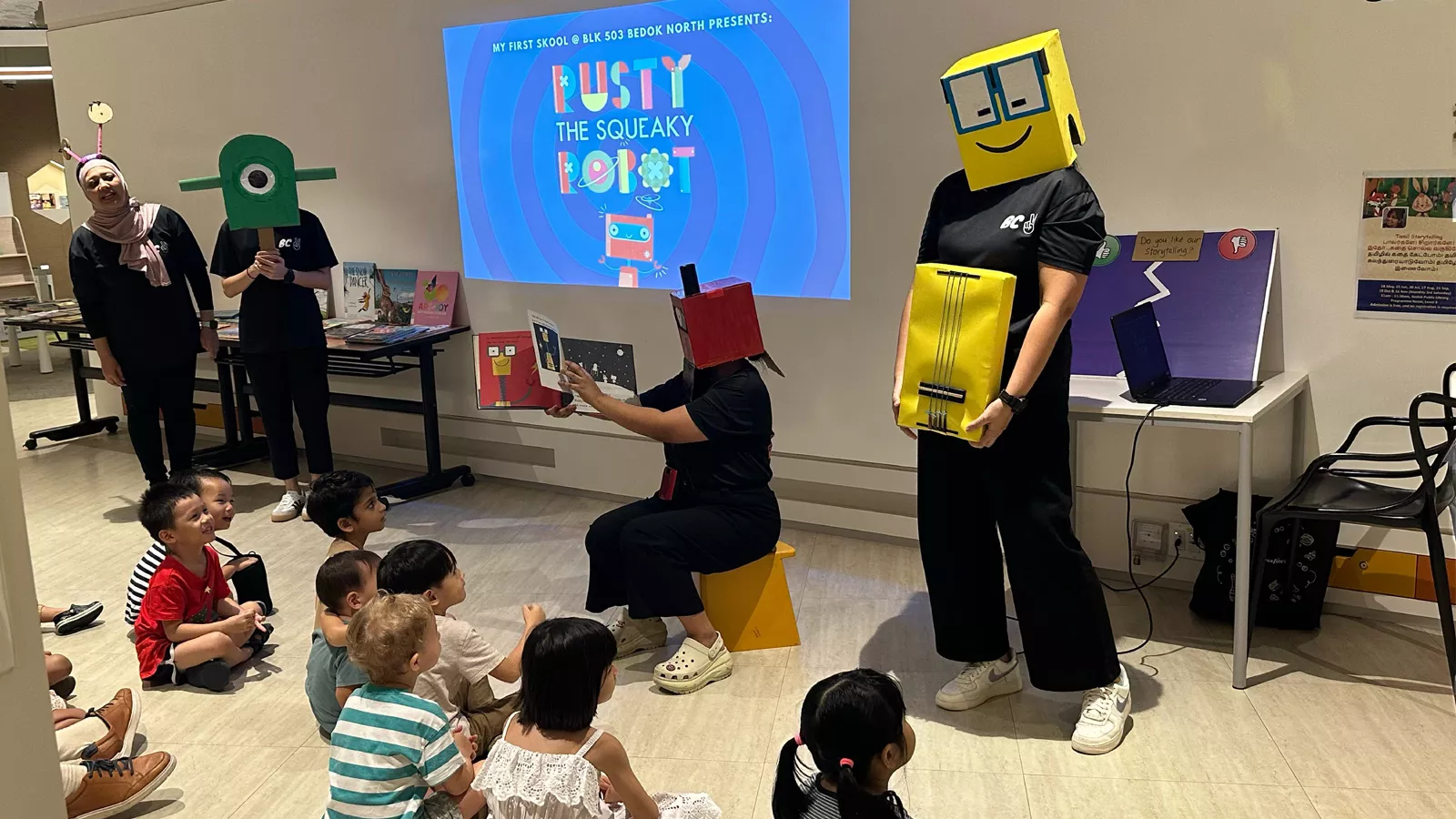 Educators use handmade props to conduct a storytelling session, while children sit captivated on the floor.