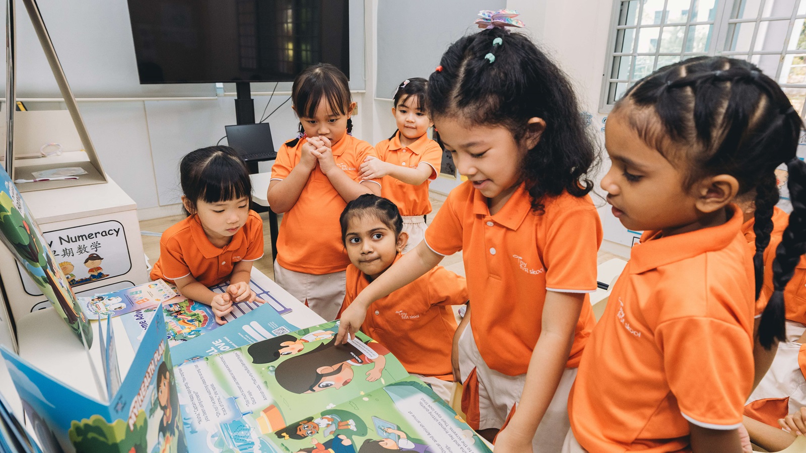 A group of children in uniform gathered in front of a book