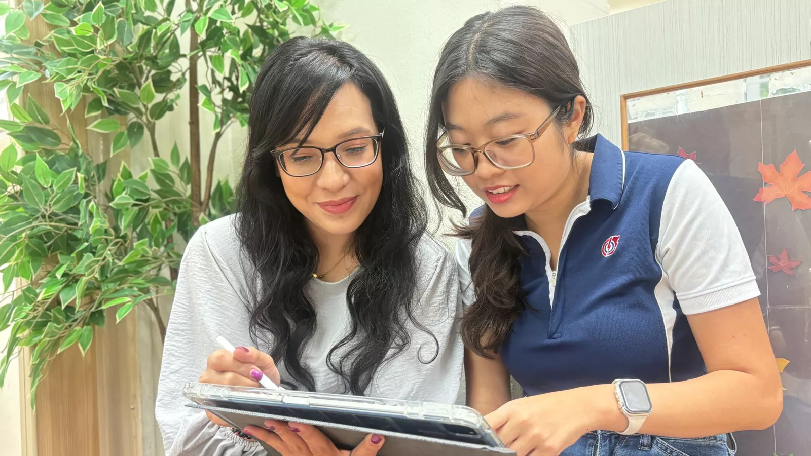 Principal Siti Nadiah and an educator look at a tablet together, focused on mentoring and professional development.