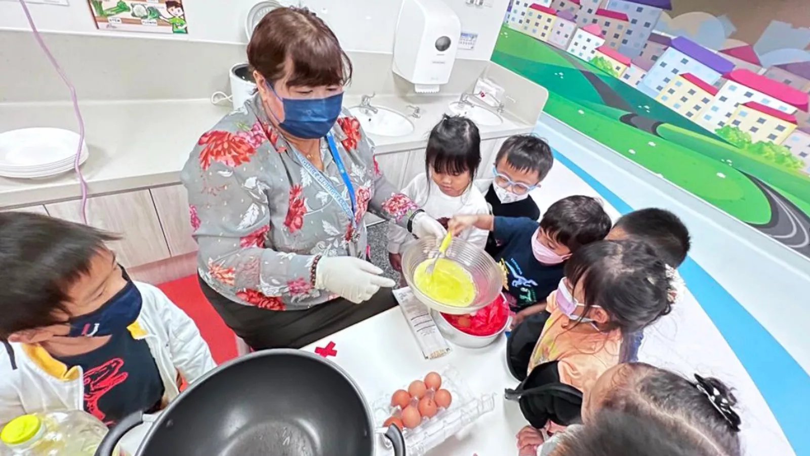Centre leader Brenda De Silva cooks with children, engaging them in a fun and educational kitchen activity.