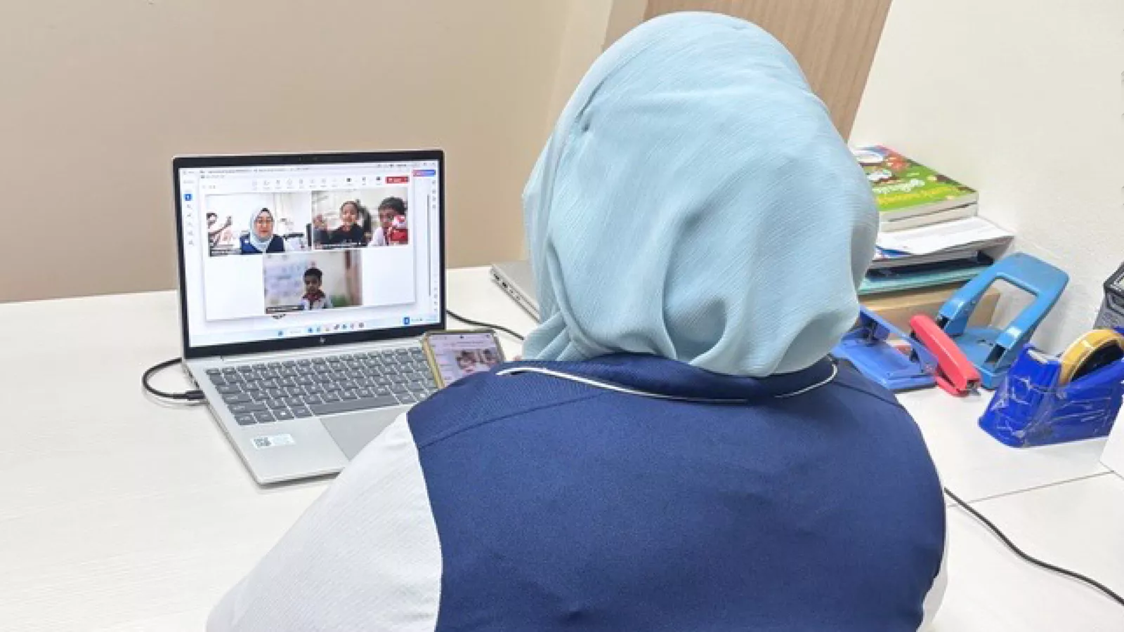 A MTL teacher conducts a virtual lesson in a quiet space, ensuring that learners on the receiving end can hear her clearly.