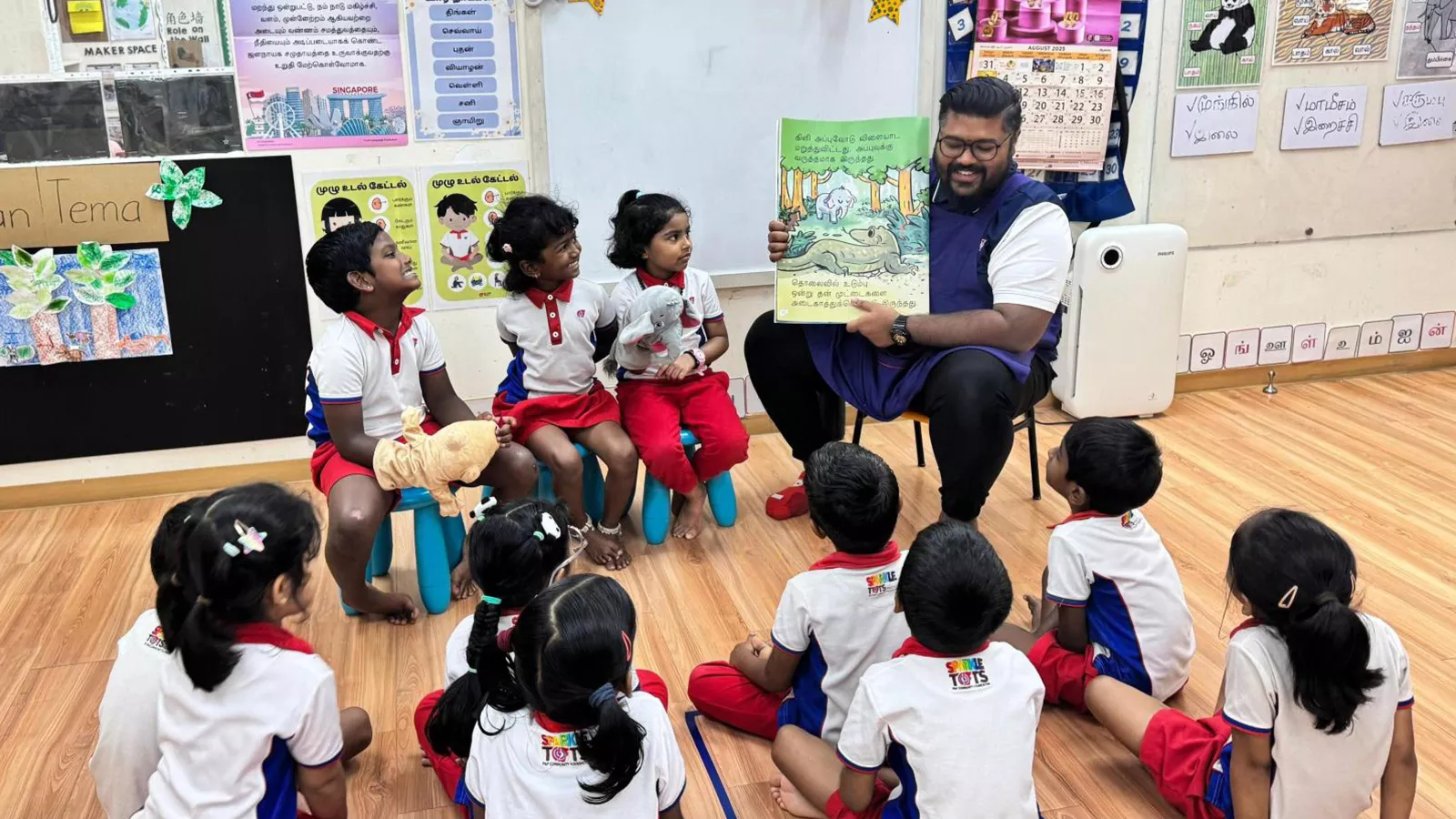 A MTL educator reads a Tamil book to children in a classroom setting, showcasing the importance of face-to-face lessons.