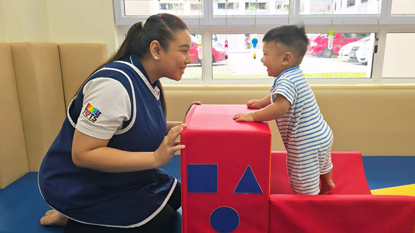 An educator and child play together in a preschool’s soft-play jungle gym, building the child’s competence and capabilities.