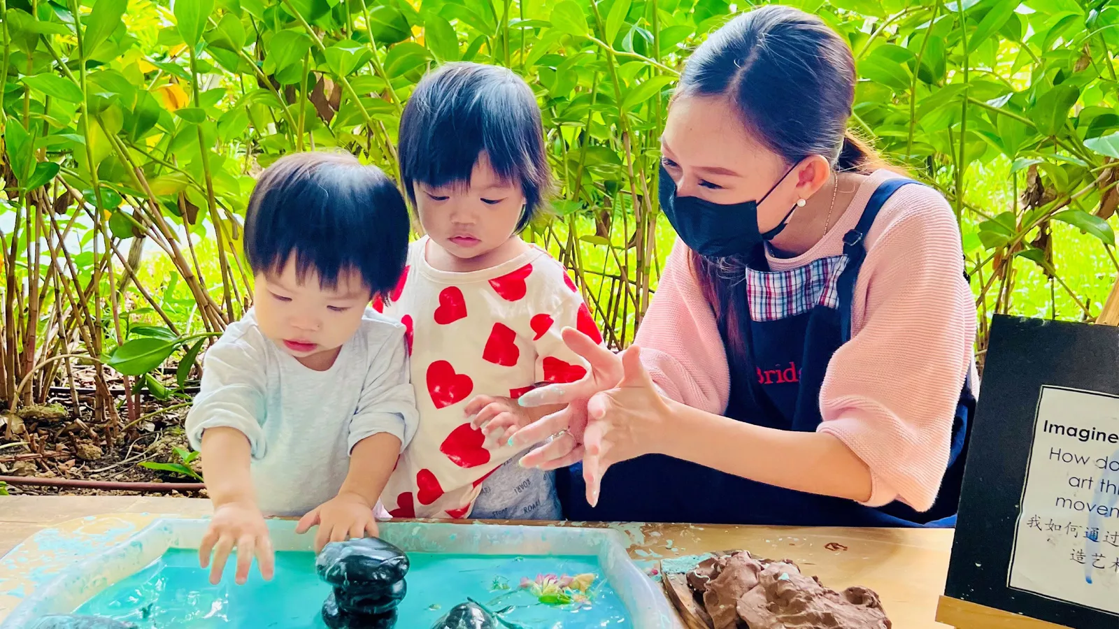 Infant educator Zurhidah Matsidah engages two children in learning through play, using goop and natural loose parts.