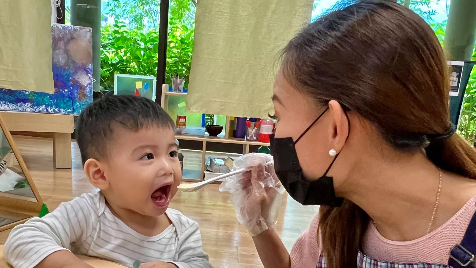 Infant educator Zurhidah Matsidah feeds a child, demonstrating 3R interactions during routine caregiving.