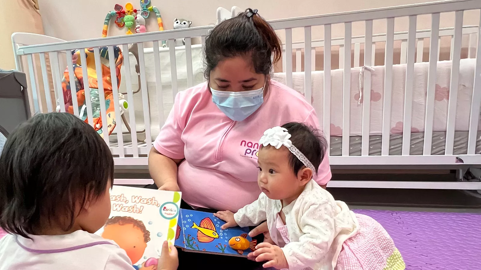 A childminder engages two infants in storybook time, creating a warm and nurturing reading environment.