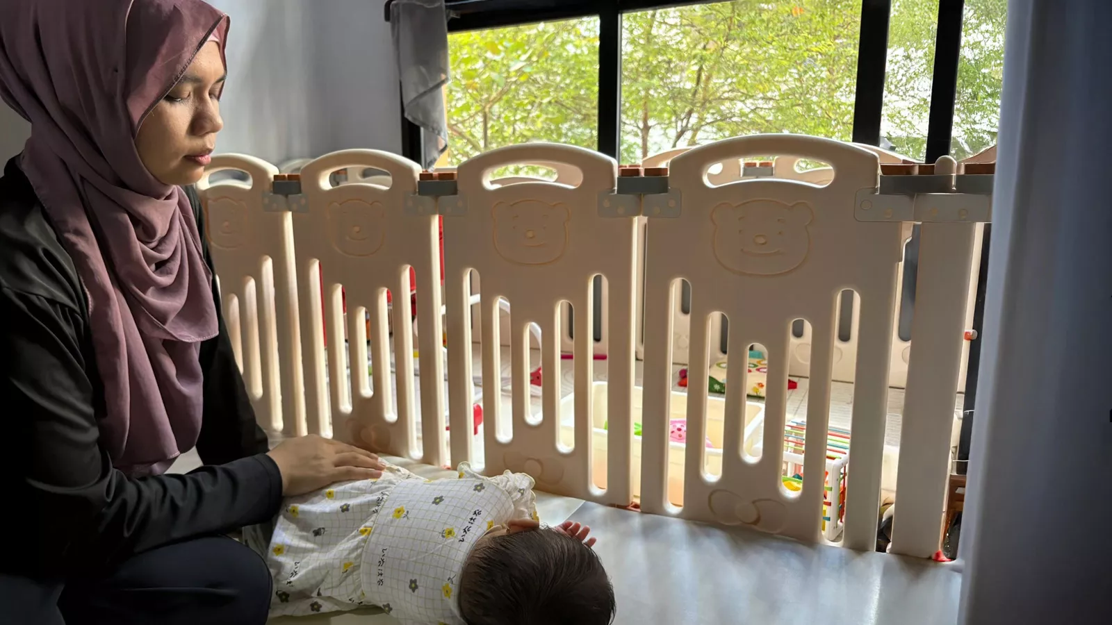 A childminder tucks a baby in for her nap, showcasing a tender interaction between caregiver and infant.