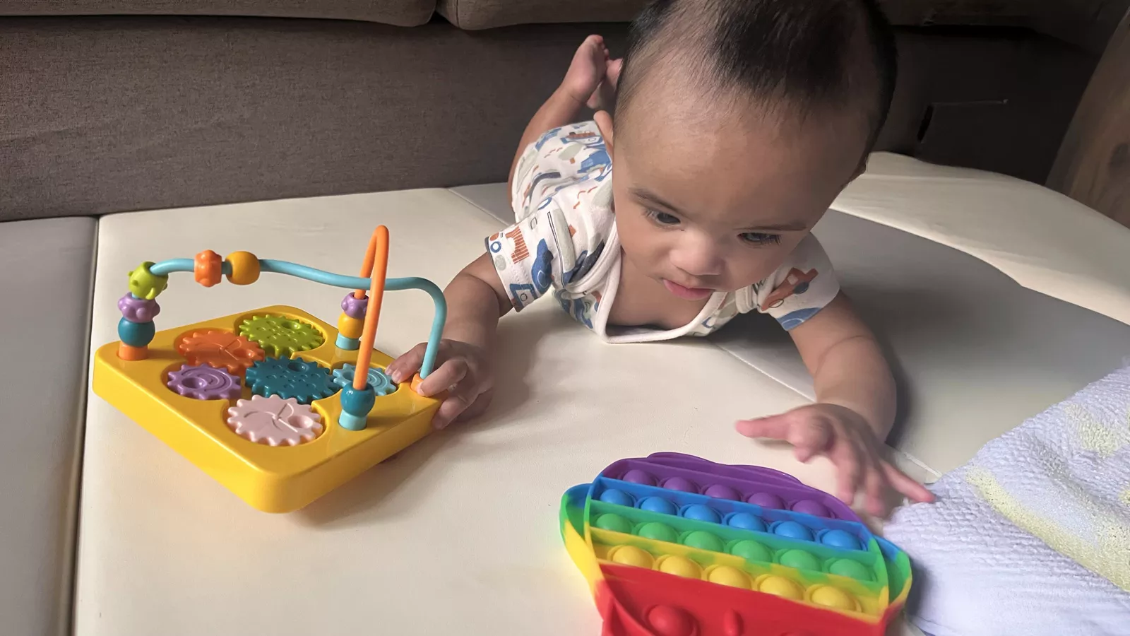 A baby lies on his tummy while playing with sensory toys, sparking curiosity and development.