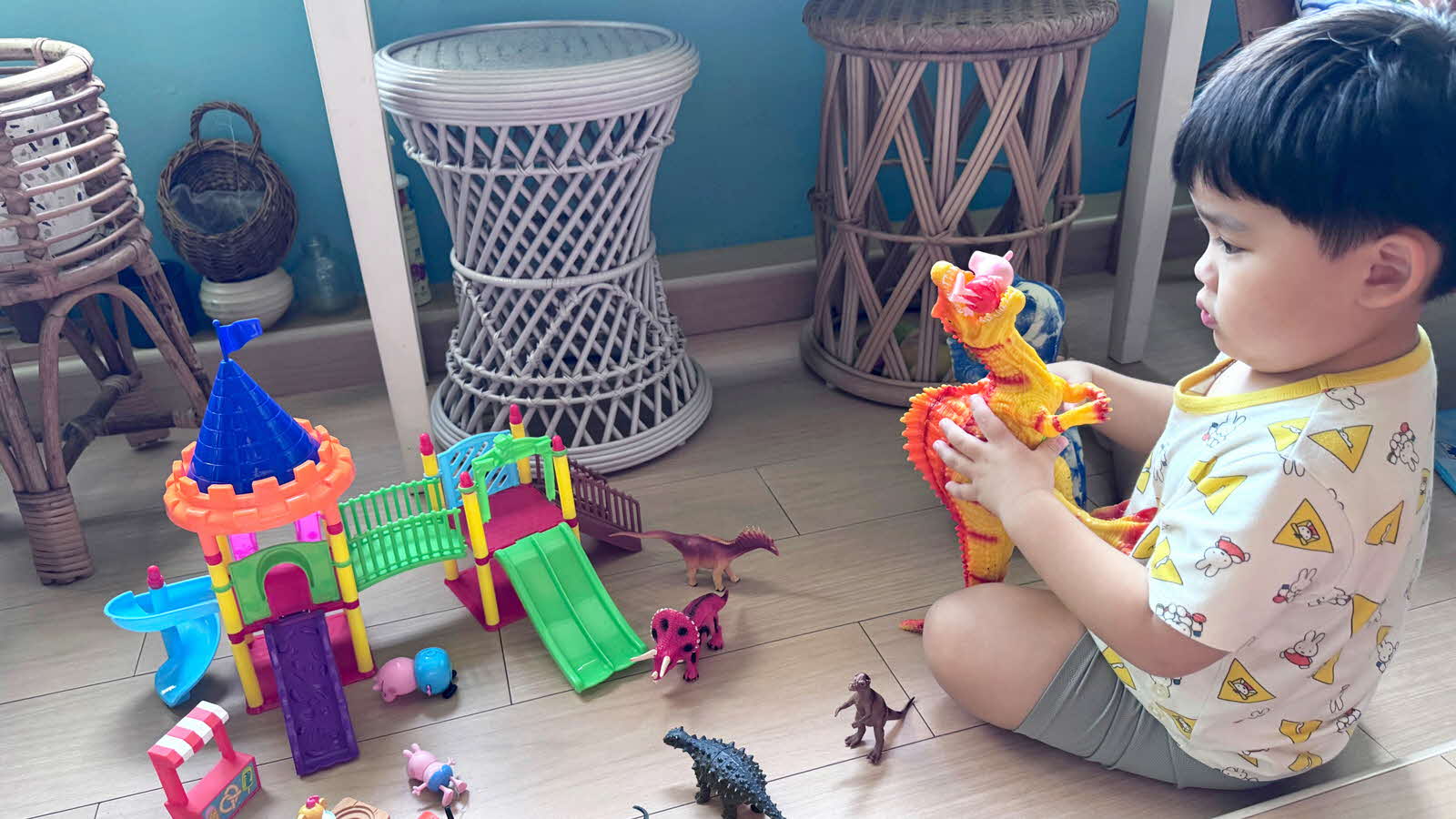 A young boy sits on the floor and plays with various toys scattered around him.