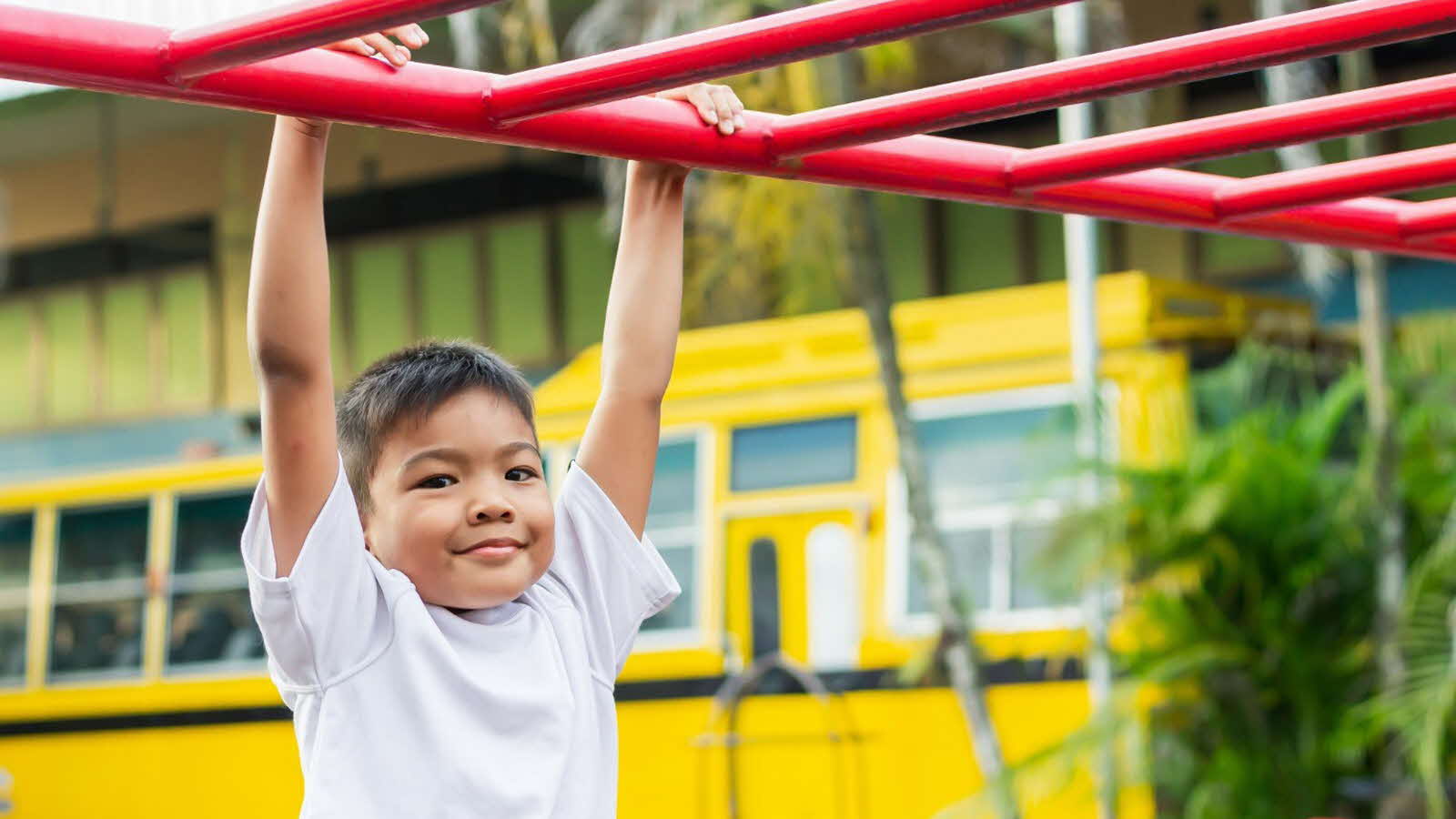 A child plays with monkey bars at the playground, enjoying the outdoors and benefitting from active play.