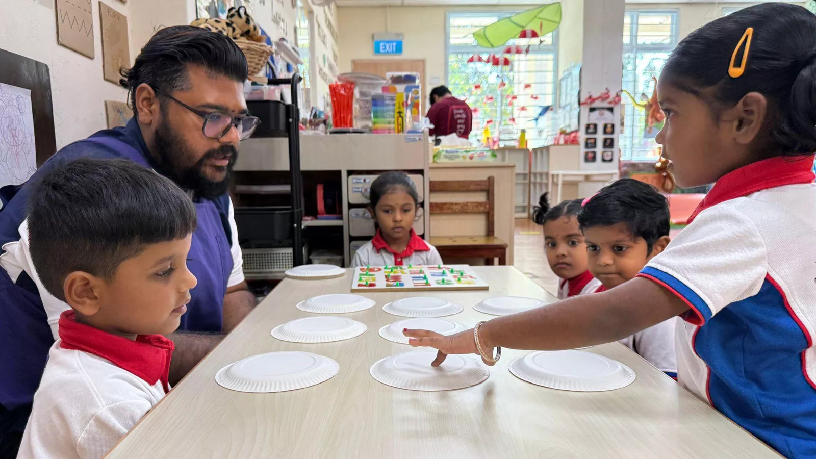 Tamil Language teacher Lesalan Bathmanathan engages preschoolers in a fun tabletop game during a face-to-face session.