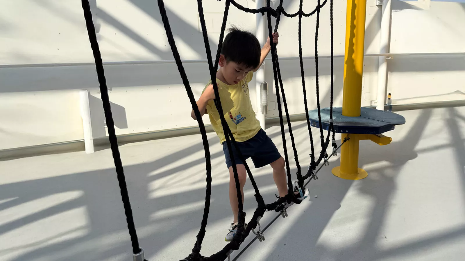A child climbs on a cargo net in a playground, learning to take risks, face challenges and solve problems on his own.