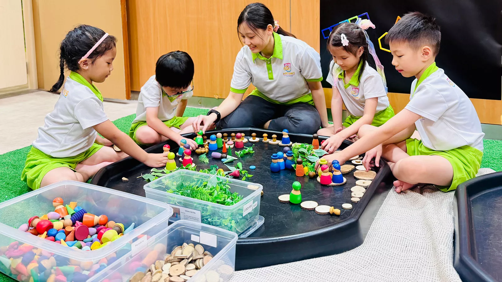 Children happily play with loose parts play items such as mandala pieces and leaves, fostering creativity and collaboration.