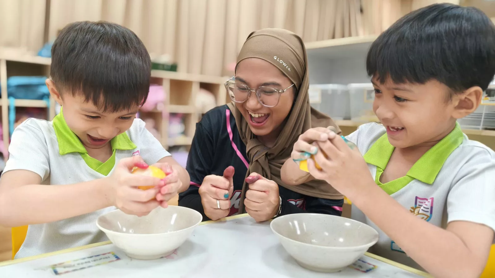 An educator guides two children in a kitchen science activity as they enjoy the hands-on, inquiry-based learning experience.
