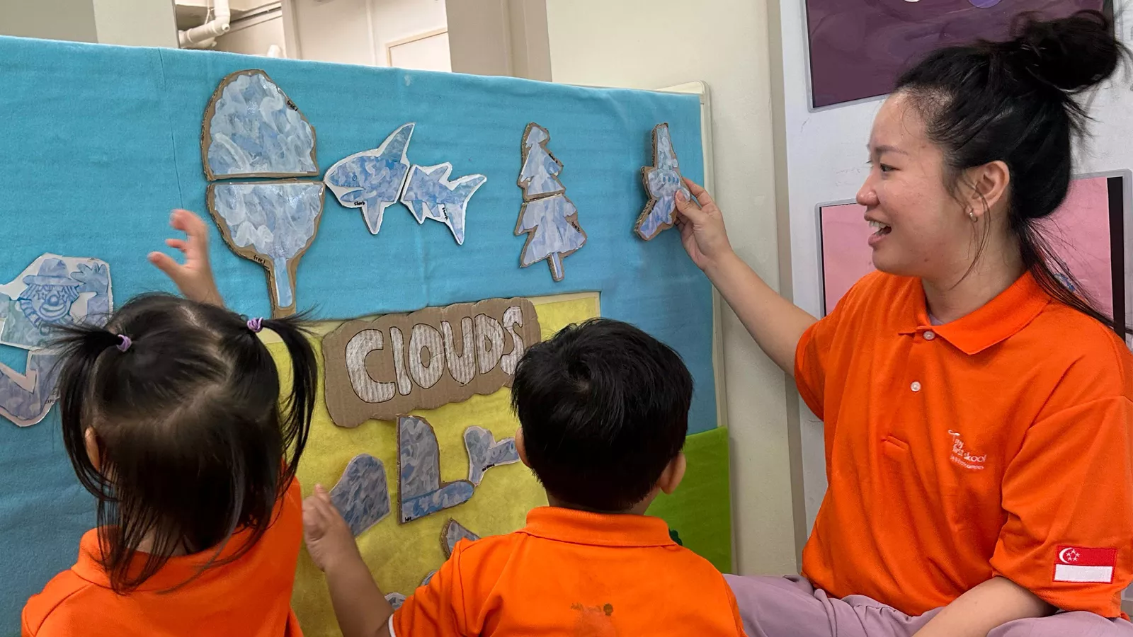 An educator engages children at a physical storyboard wall, as an example of quality early childhood education.