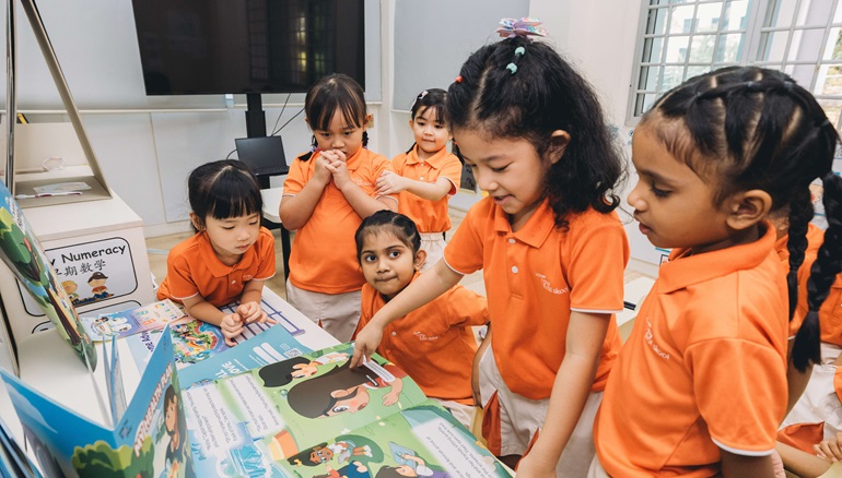 A group of children in uniform gathered in front of a book