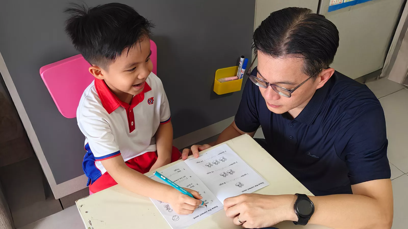 Parent Kelvin Soh helps his K2 child with his writing practice at home, as part of the preparation for primary school.