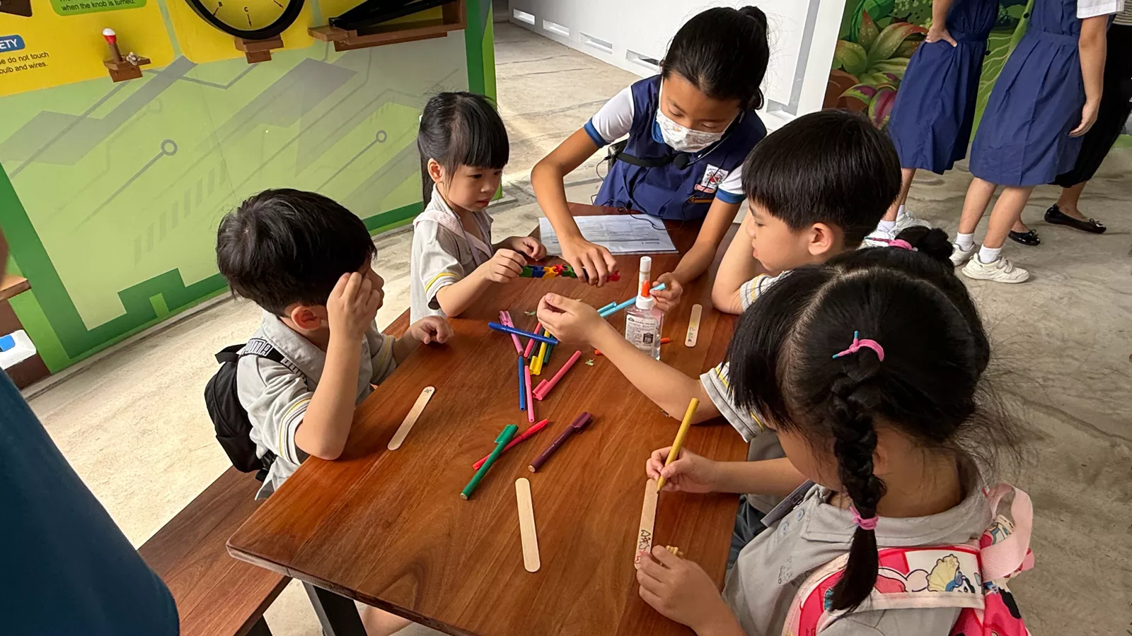 A primary school student helps a group of preschoolers in an art and craft activity, as part of their primary school visit.