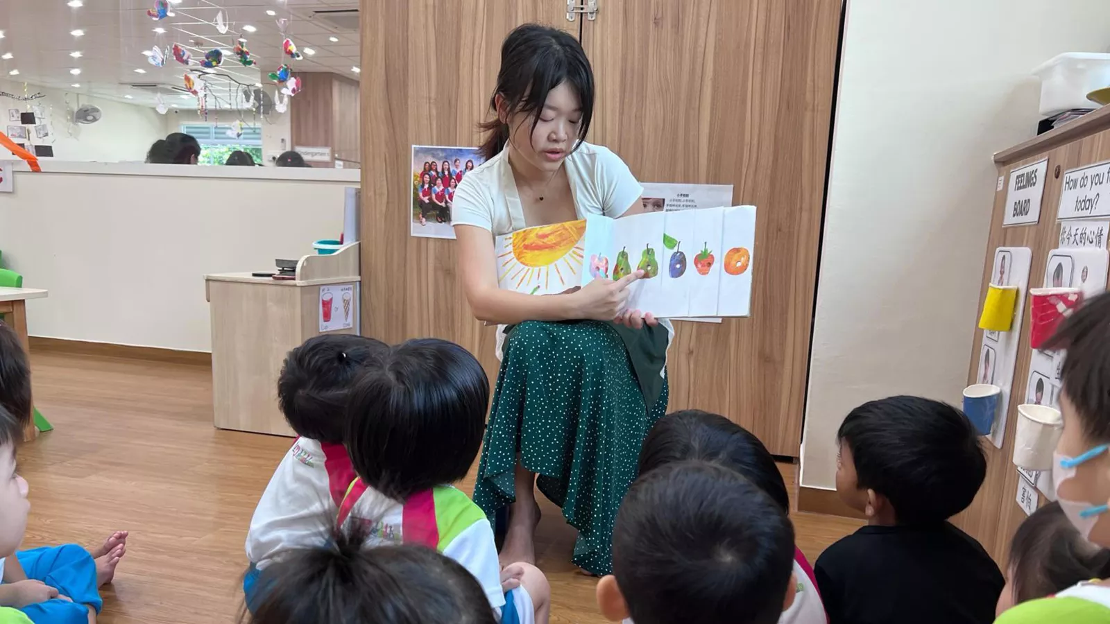 Parent Kow Bi Xia reads a story to children in a classroom setting, representing positive parent-preschool partnership.