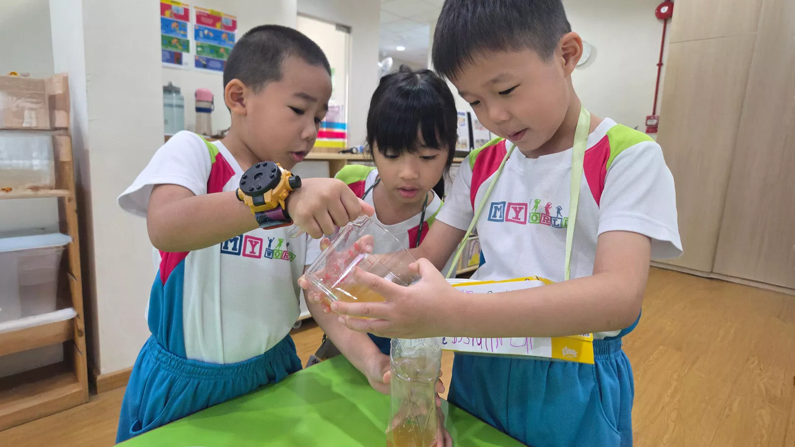 Three children engage in a hands-on juice-making activity, learning to problem-solve and cooperate while having fun.