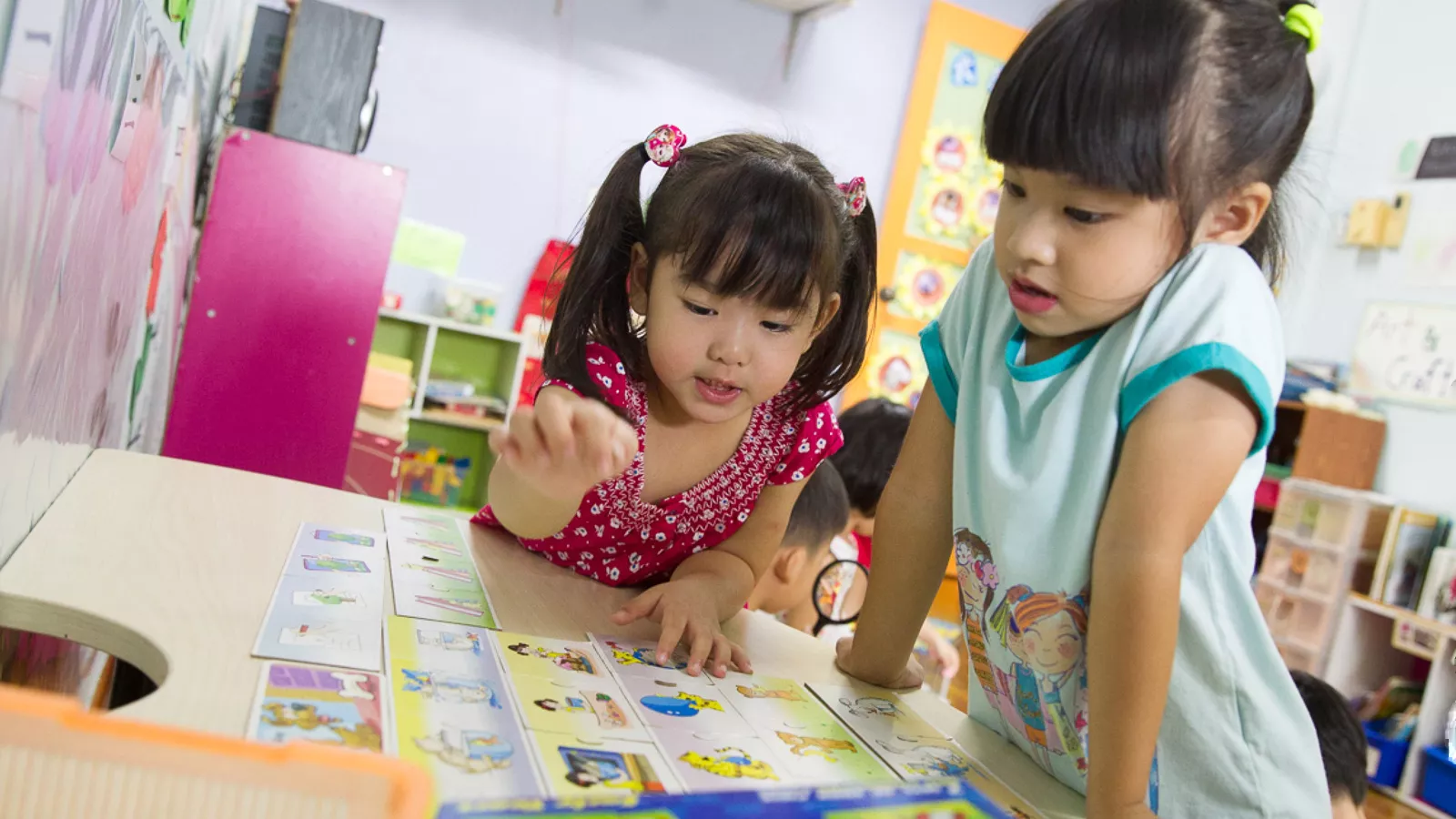 Two girls engage in a fun board game, demonstrating the value of learning through play in the early years.