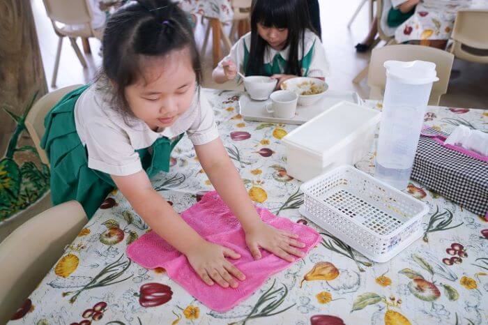 Children use a cloth to clean up after their meals