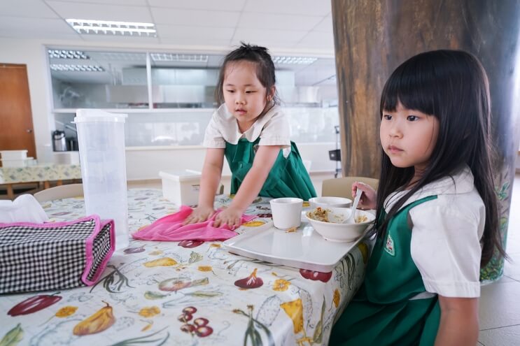 Children use a cloth to clean up after their meals